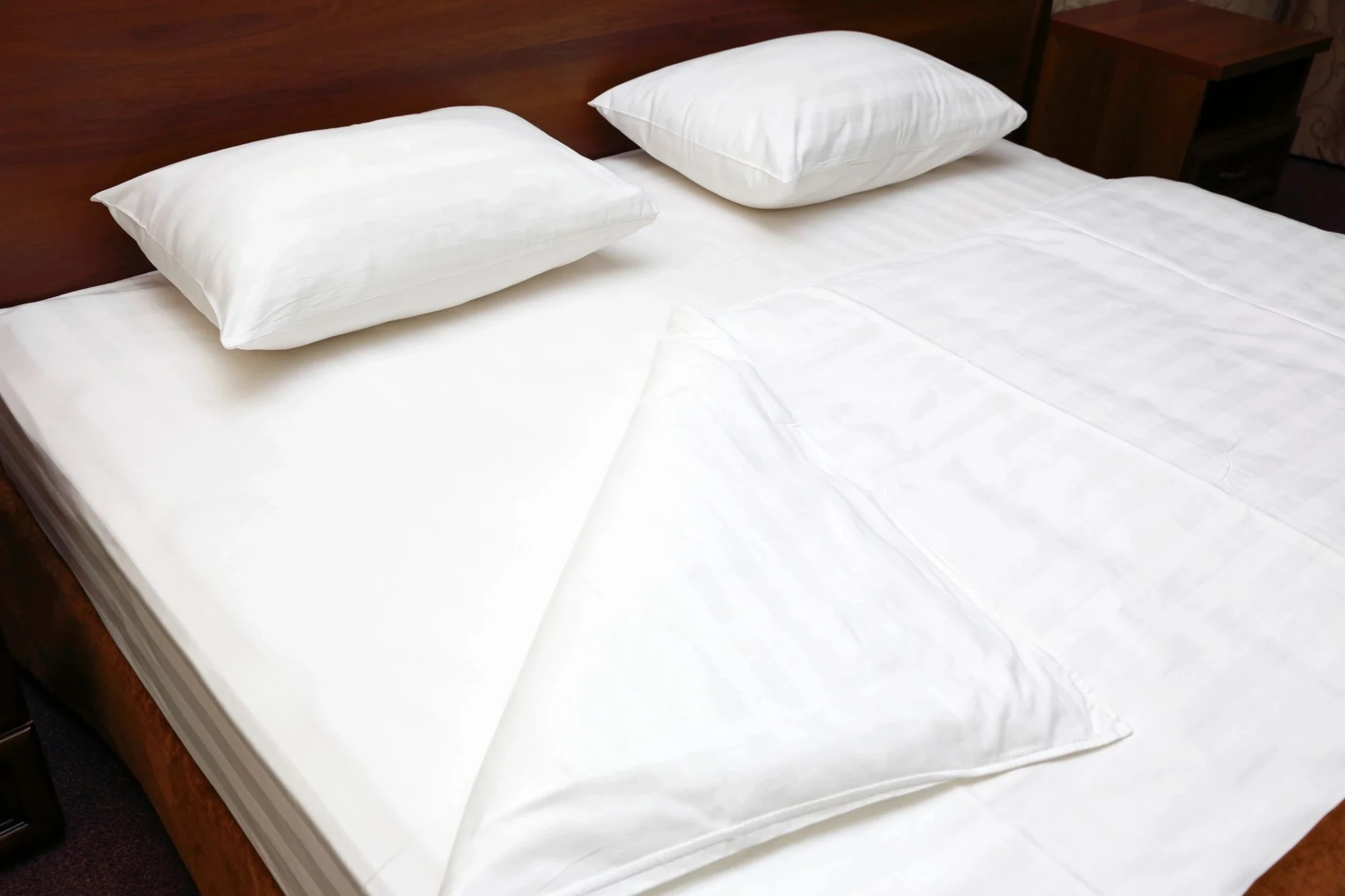 A bed with white sheets and pillows on it