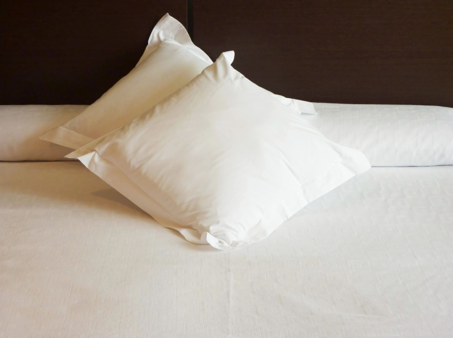 A white pillow on top of a bed.